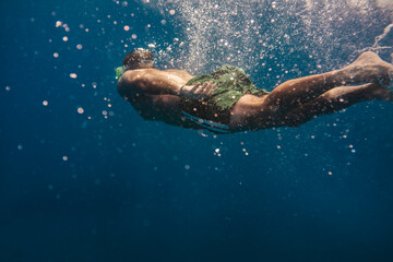 Fototapeta na wymiar Man swimming underwater into the ocean