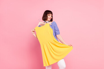 Photo portrait of pretty woman fitting clothes dreamy choosing dress isolated on pastel pink color...