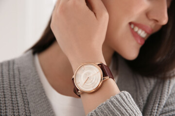 Woman with luxury wristwatch on light background, closeup - obrazy, fototapety, plakaty