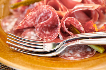 Slicing raw smoked sausage in a plate is on the table.