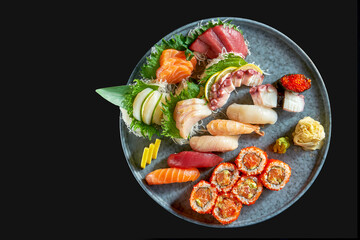 An appetizing sushi set consisting of various nigiri. sashimi and uramaki with salmon, avocado and tobiko caviar. Japanese traditional cuisine. Food delivery. Isolated on black