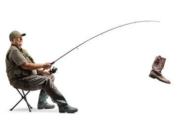 Mature fisherman sitting on a chair with a fishing rod and an old boot on the hook