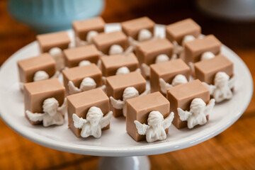 Fototapeta na wymiar Prato de doces de festa de batizado enfeitados com anjinhos de chocolate branco.