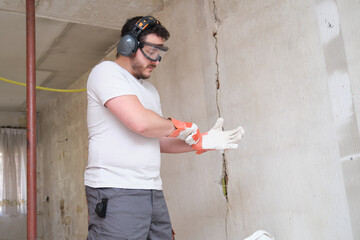 Builder putting on protective gloves, wearing safety glasses and hearing protection. Safety at work.