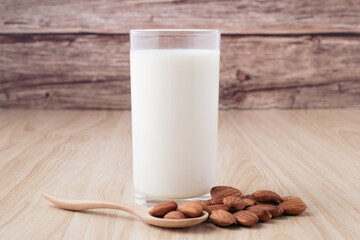 almond milk in glass on wood background with nuts around the bowl.selective focus.front view.copy space.