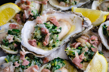 Herb Butter Oysters with Prosciutto in a Cast-Iron Skillet: Cooked oyster appetizers on a layer of kosher salt