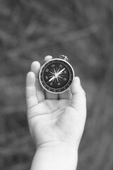 Old classic navigation compass in hand on natural background as symbol of tourism with compass, travel with compass and outdoor activities with compass