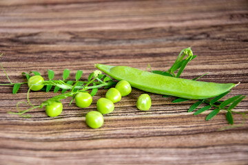 Green peas close-up on a wooden background. Pea leaves and pods.