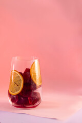 a glass beaker filled with red cubes of lda, on the sides of the glass there are orange curls