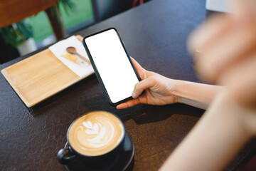 Obraz premium Close up of woman using mobile blank smart phone and credit card sending massages in the coffee shop