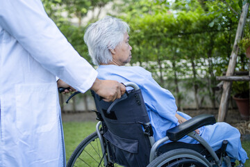 Fototapeta premium Doctor help and care Asian senior or elderly old lady woman patient sitting on wheelchair at park in nursing hospital ward, healthy strong medical concept.
