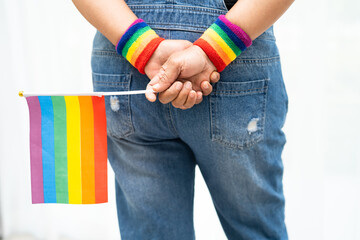 Asian lady wearing blue jean jacket or denim shirt and holding rainbow color flag, symbol of LGBT...