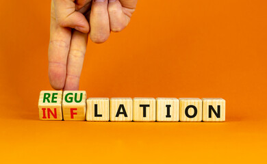 Inflation or regulation symbol. Businessman turns cubes and changes the word inflation to regulation. Beautiful orange table, orange background, copy space. Business, inflation or regulation concept.