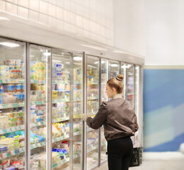 Woman choosing frozen food from a supermarket freezer..