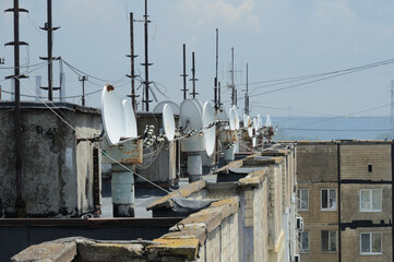 satellite TV antennas are installed on the roof of a multi-storey residential building