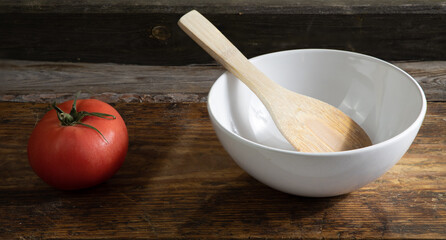 Biała miska i pomidor na starych drewnianych deskach