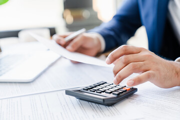Businessman counting bills savings investments dividends on calculator, managing money to make...