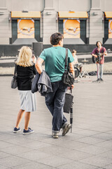 Married couple watching and taking pictures of street musicians, view from behind. Regular people...