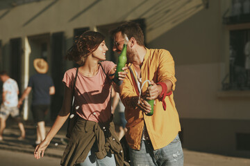 Young couple dancing on the street and opening beer