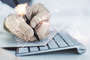 Abstract creative world map and hand writing in notebook on background with laptop, international trading concept. Multiexposure