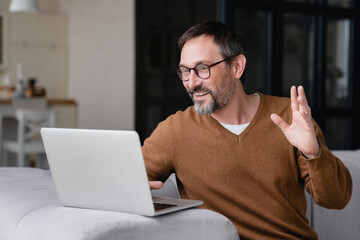 Happy mature middle-aged man businessman freelancer father having online video call conference conversation on laptop remotely with colleagues, friends, children, doctor`s appointment. - obrazy, fototapety, plakaty