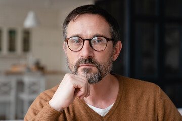 Front view portrait of a confident thoughtful pensive Caucasian middle-aged mature man teacher father freelancer wearing glasses looking at camera at home.