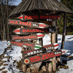 Touristic information signs under a wooden roof, on the way to Zygmuntowka mountain shelter. Snowy winter day. Owl Mountains, Sudetes, Poland.  © Kati Lenart