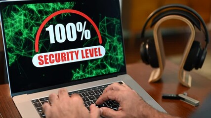 Laptop computer with security motion graphic showing 100% security with headphones and in background