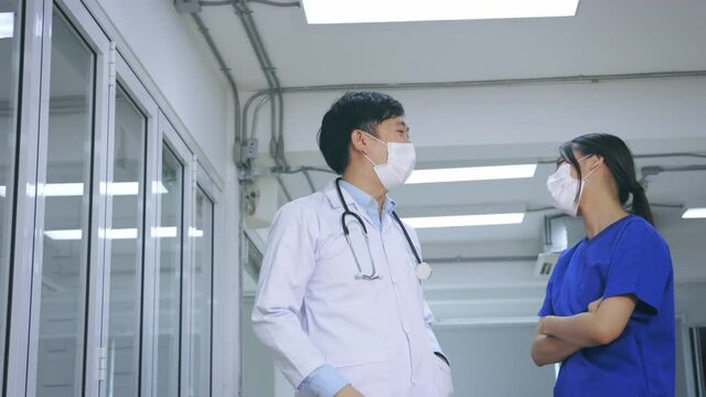 Happy And Young Male And Female Asian Team Of Doctor And Nurse Wearing Uniform And Lab Coat With Stethoscope And Surgical Mask Giving High Five To Each Other. High Quality 4k Footage