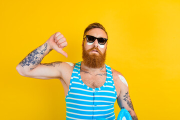 man with tattoos and swimsuit puts on sunscreen