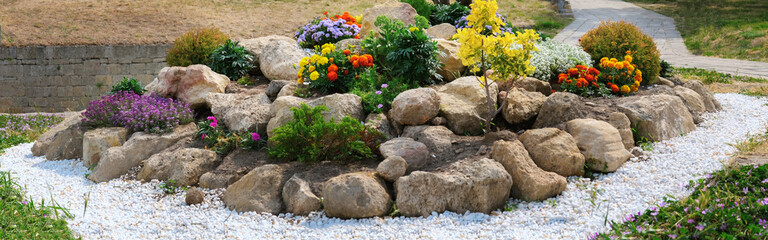 panorama round flower bed of flowers and stones - obrazy, fototapety, plakaty