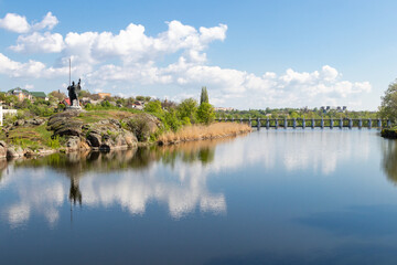 Fototapeta premium green coast of a beautiful small river with white clouds in reflection