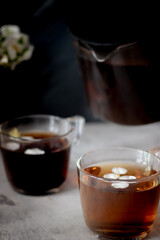 There is a teapot and two cups of black tea on the table