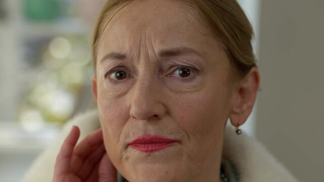 Close-up wrinkled face of middle aged Caucasian woman looking at camera. Headshot portrait of sad desperate elegant wealthy lady touching wrinkles. Frustration and aging
