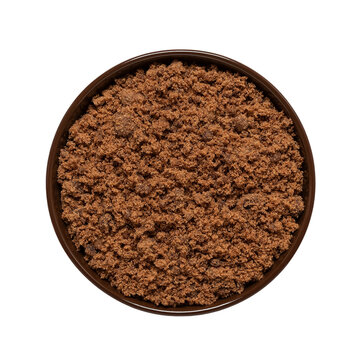 Cane brown muscovado sugar in a bowl isolated on white background. Top view. Indian sugar.