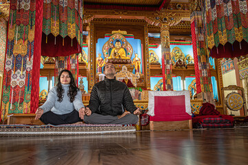 Obraz na płótnie Canvas couple meditating isolated inside buddhist monastery at morning from low angle