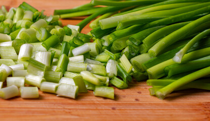 Chopped green spring onions on wooden board.