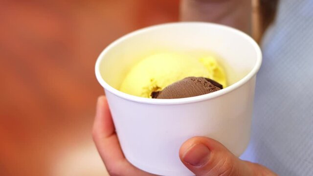 Close-up. Woman eating delicious ice cream from a cup spoon 4k footage.
