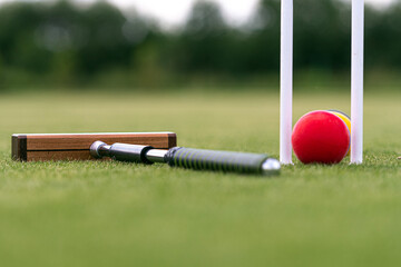 croquet mallet, wicket and colorful balls on a lawn