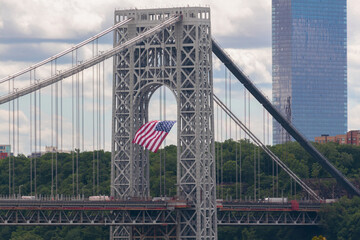 an American flag hangs from the New Jersey side suspension tower of the George Washington Bridge, a double deck suspension bridge connecting Manhattan to New Jersey across the Hudson River