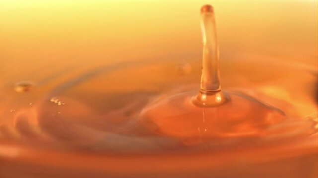 The super slow motion drop falls into the apple juice with splashes. On a yellow background. Filmed on a high-speed camera at 1000 fps.