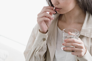 Young woman take pill, holding glass of water