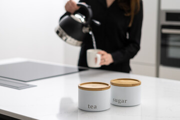 Woman pouring hot water from kettle into mug