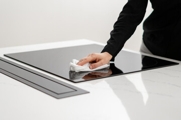 Woman polishing her ceramic induction cooktop with tissue
