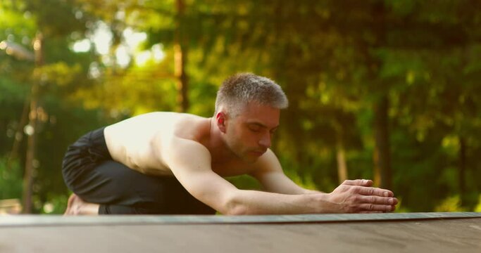 Man practicing yoga.Yogi snading on knees with hands stretched in front.Guy moving head up and down
