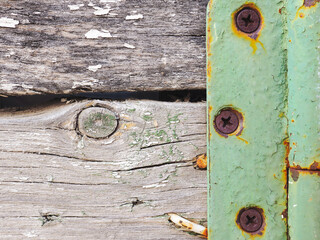 Fragment of a rustic gate in a fence close-up. Old gray weathered wooden beams and door hinge. Vintage illustration or background on a rural theme. Rusty screws and nails, paint residues. Strong macro