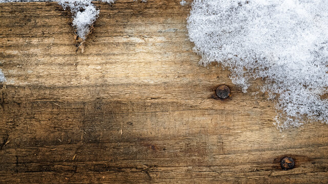 Wooden winter brown background with pieces of white snow and copy space