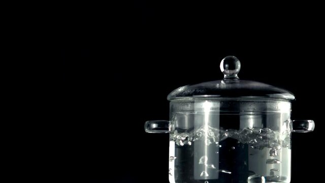 Super slow movement of the pan with boiling water. On a black background. Filmed on a high-speed camera at 1000 fps.High quality FullHD footage