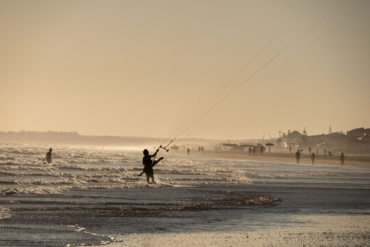 silhouette man with kitesurf kite in the sunset of the beach of huelva