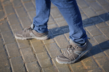 Man's legs in sneakers and blue jeans